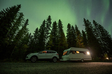 Fototapeta na wymiar Aurora shining over Camping Caravan in Swedish forest Tannforsen Waterfall Northern Lights color sky Sweden, Scandinavia