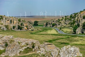 Asphalt road full of cars in a rocky field in Dobrogea, Romania with windmills on the background