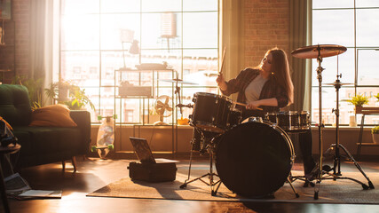 Fototapeta na wymiar Young Female Playing Drums During a Band Rehearsal in a Loft Studio with Warm Sunlight at Daytime. Talented Drummer Girl Practising Before a Live Concert on Stage With Other Musicians.