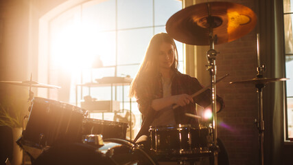 Fototapeta na wymiar Expressive Drummer Girl Playing Drums in a Loft Music Rehearsal Studio Filled with Light. Rock Band Music Artist Learning a New Drum Solo. Portrait of Woman Enjoying Creating Rythm.