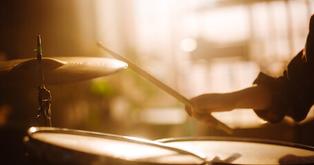 Close Up Cinematic Portrait of a Young Female Playing Drums, Using Cymbals in a Loft Music Rehearsal Studio Filled with Warm Sunset Light. Rock Band Music Artist Learning a New Drum Solo.