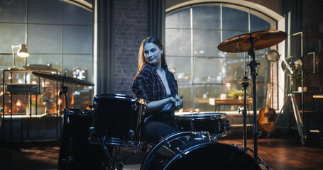 Fototapeta na wymiar Expressive Drummer Girl Playing Drums in a Loft Music Rehearsal Studio at Night. Rock Band Music Artist Learning a New Drum Solo. Woman Practicing Before Big Concert with Audience.