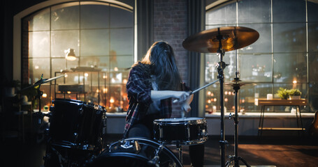 Expressive Drummer Girl Playing Drums in a Loft Music Rehearsal Studio at Night. Rock Band Music Artist Learning a New Drum Solo. Woman Practicing Before Big Live Concert with Audience.