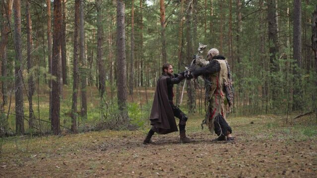 Large arc fights off attack and pushes knight on ground on dense forest glade slow motion. Fairy tail creature defends native land from conqueror