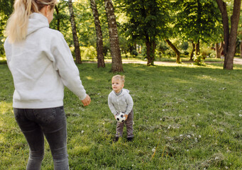 Fototapeta premium Happy smiling mother and sons playing with football ball outdoors