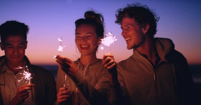Night, group of friends and sparklers at party, having fun or enjoying quality time together. Sunset, sparks or freedom of gen z people in celebration of new year at outdoor rave holding firecrackers