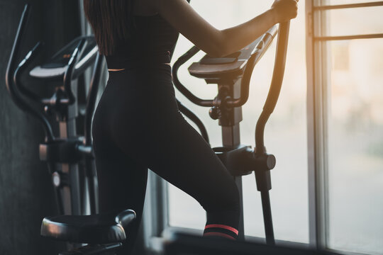 Crop picture, back view, sportswoman exercising on elliptical machine in the gym, determination to cardio lose weight, makes her healthy. exercise elliptical machine woman fitness sport concept.