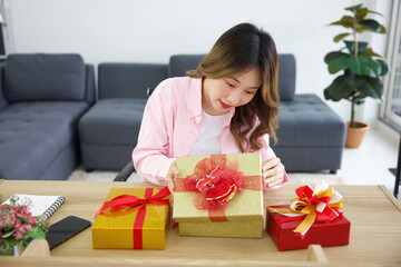 young woman looking and opening to gift box on a table in the office