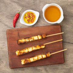Grilled Rennet or Coalho cheese on a wooden board with sugar syrup and pepper