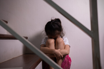 Adorable asian girl who expresses her sadness emotion on house stair alone shows concept of depression, emotional pain and unhappiness of child which might due to abusement from family and school.