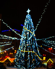 Bokeh silhouette of Christmas tree. Christmas tree with decorations and lights bokeh in a black background, outdoor