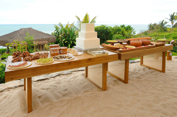 outdoor birthday cake table on the beach,  condensed milk candy balls, candy balls, cake and candy table on the beach sand, cake and candy table, horizon line