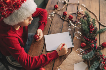 Christmas helper child writing letter to Santa Claus letter in red hat