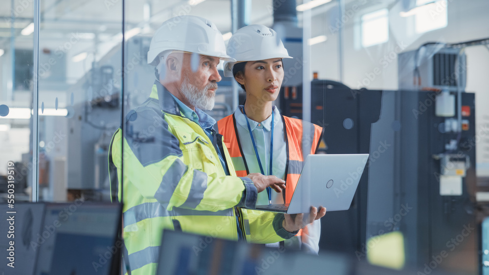Poster two professional heavy industry employees wearing hard hats at factory. checking and discussing work