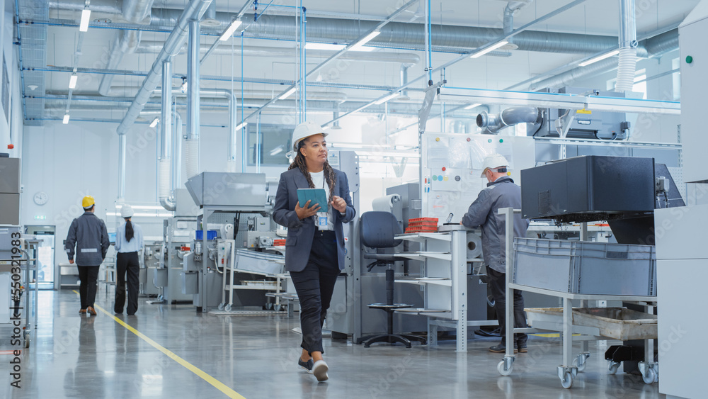 Fototapete Portrait of a Black Female Engineer in Hard Hat Walking and Using Laptop Computer at Electronic Manufacturing Factory. Technician Working on Daily Tasks and Research and Development Data.