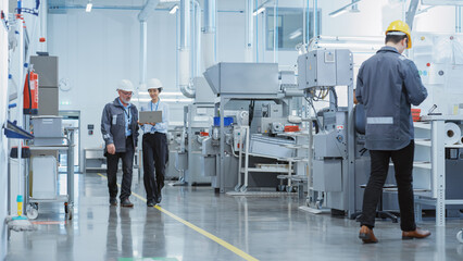 Two Professional Heavy Industry Employees Wearing Hard Hats at Factory. Walking and Discussing...