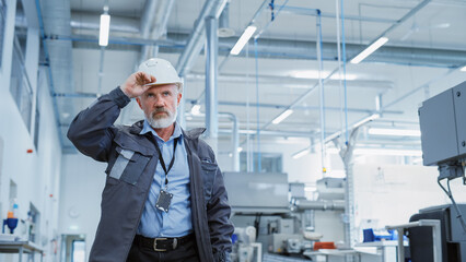 Portrait of a Middle Aged, Successful Male Engineer Putting On a White Hard Hat a, While Walking at Electronics Manufacturing Factory. Heavy Industry Specialist Starting a Work Day.