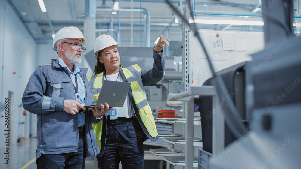 Poster portrait of two heavy industry employees in hard hats at factory. checking and discussing industrial