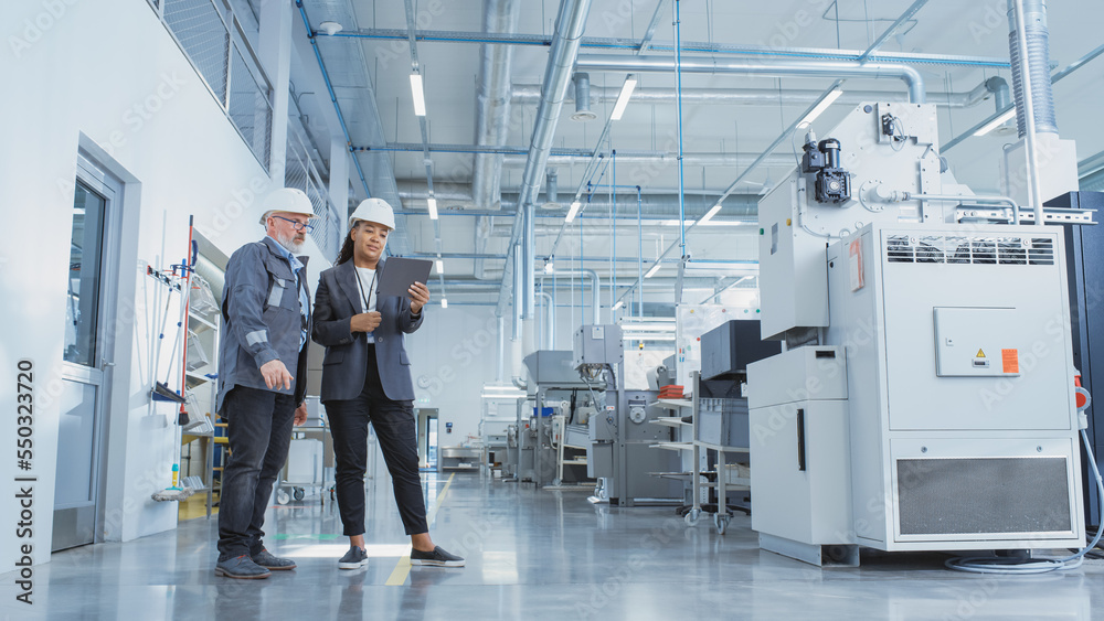 Poster portrait of two heavy industry employees in hard hats at factory. checking and discussing industrial