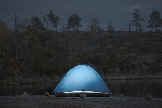 Camping on the granite shore. Illuminated tent.