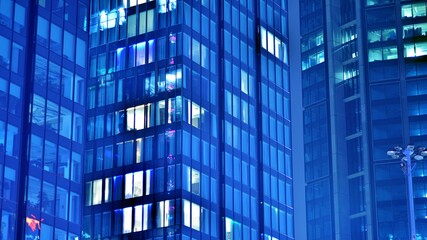 Pattern of office buildings windows illuminated at night. Glass architecture ,corporate building at night - business concept. Blue graphic filter.