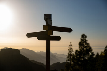 signpost in the mountain at sunset. Silhouette of a sign with four directions with mountains and sunset in the background - 550327128