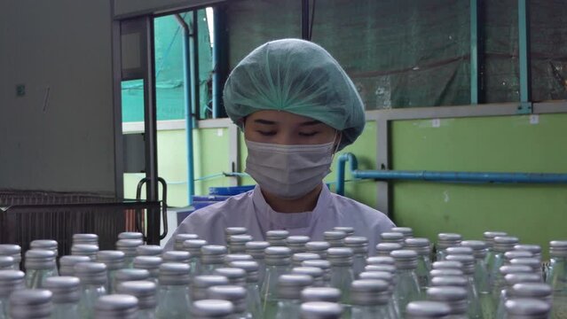 Quality control woman and manager wearing a lab coat to checking juice industrial process at factory. Teamwork at production line successful concept.	