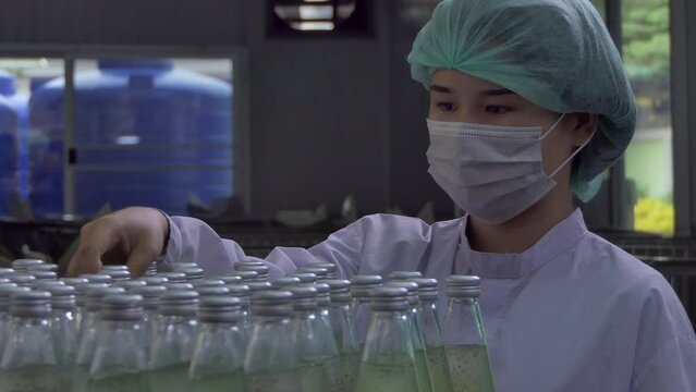 Quality control woman and manager wearing a lab coat to checking juice industrial process at factory. Teamwork at production line successful concept.	