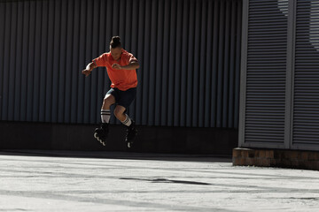 Young man in rollers and knee socks jumping on city street at daytime.