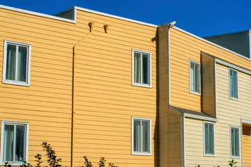 Modern apartment building with orange and wooden slat and pannel house with building facade exterior in late afternoon sun