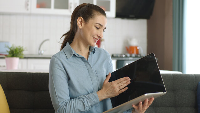 Young Woman Holding Her Laptop Like A Book. Young Woman Switching Pages As If Reading A Book On Her Laptop. The Woman Is Surprised By What She Sees On Her Laptop. Future Technology.