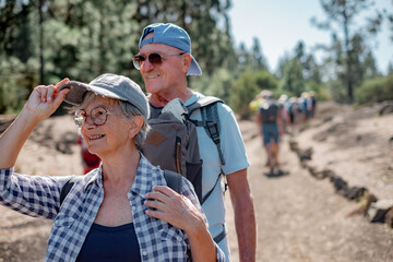 Happy caucasian senior couple walking in footpath in mountain excursion smiling enjoying free time and adventure in nature, elderly retired people and healthy lifestyle concept © luciano