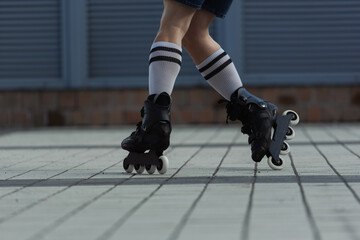 Cropped view of skater in knee socks and roller blades riding on street.