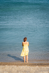 une femme de dos regardant pensivement la mer. Une femme triste à la mer. Une femme avec une robe...
