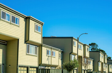 Appartment buildings with block style design and cream or beige exterior made of wood with visible windows and blue sky