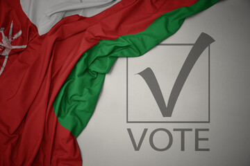 waving colorful national flag of oman on a gray background with text vote. 3D illustration