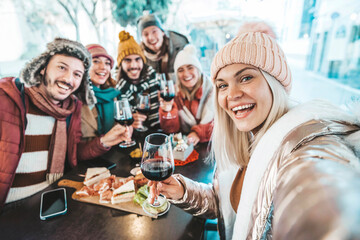 Happy friends celebrating Christmas and new year eve party together - Cheerful young people holding wine glasses taking selfie picture sitting at bar restaurant - Beverage and winter holiday concept