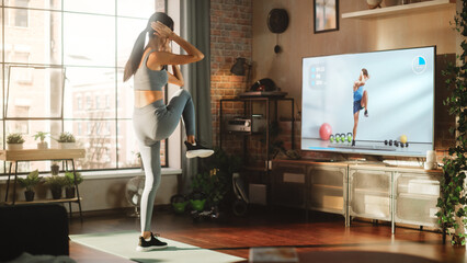Home Training: Beautiful Girl Training with Personal Trainer via Online Video Tutorial. Authentic Woman Using Workout Service in Fitness Streaming App for Virtual Training. Energetic Side Back View