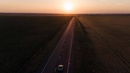 the car drives along the highway into the sunset pink sky