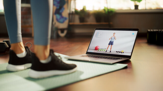 Woman Workout, Watching Trainer on Laptop, via Online Video Tutorial while Virtual Training at Home. Athletic Woman Using Streaming Service Fitness Subscription. Low Ground Shot of Legs and Laptop