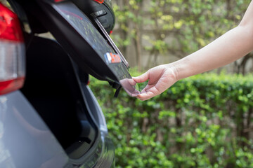 Hand of woman open car back trunk hood. Check in the car and clean