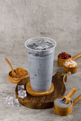 Boba or tapioca pearls is taiwan bubble milk tea in plastic cup with charcoal flavor on texture  background, summers refreshment.