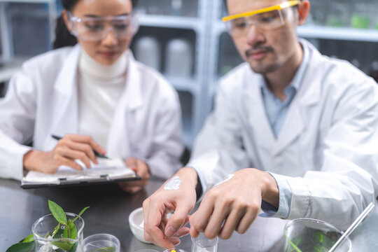 Beauty eco cosmetic research and development concept, Scientist or Pharmacist applying moisturizer lotion on her hand for efficacy testing of natural organic skincare products in laboratory