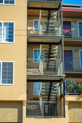 Modern apartment staircase with wire or metal design and visible beige stucco building facade or exterior with escape balconies