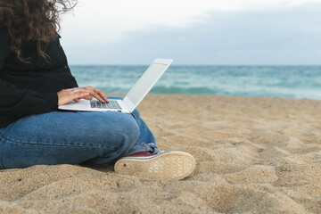 Anonymous woman using laptop on beach