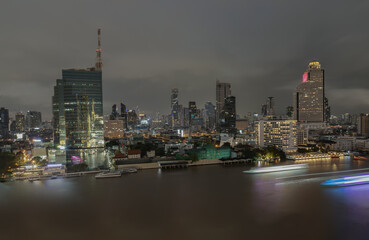Skyscrapers in the business district along chaopraya river of Bangkok city at night under Sprinkling rain. Rainy season, No focus, specifically.