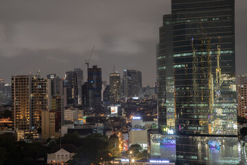 Fototapeta na wymiar Skyscrapers in the business district of Bangkok city at night under Sprinkling rain. Rainy season, No focus, specifically.