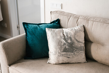 Decorative pillows of gray and turquoise color on the sofa in a cozy living room