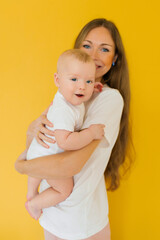 Happy, cheerful Caucasian mom holds a laughing little son in her arms