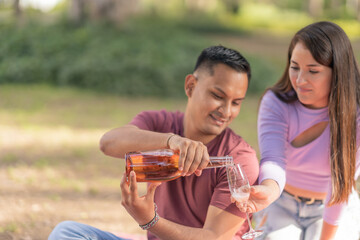 Happy diverse couple having wine in park